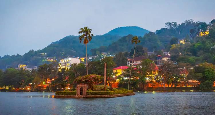 Les lumières du soir de Kandy scintillant sur le lac avec les collines environnantes.