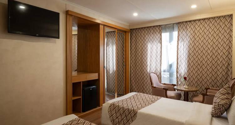 Cabine de navire de croisière à lits jumeaux avec rideaux à motifs, coin salon et armoire intégrée.