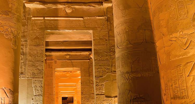 Les colonnes illuminées et les murs hiéroglyphiques créent un corridor doré à l'intérieur d'un temple égyptien antique la nuit.