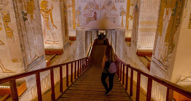 Un voyageur descend un escalier en bois dans une chambre funéraire égyptienne antique aux couleurs vives.