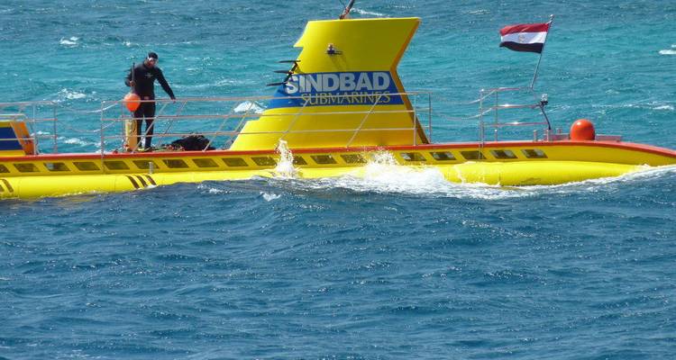 Le sous-marin Sindbad jaune vif navigue sur les eaux turquoise éclatantes avec le drapeau égyptien qui flotte.