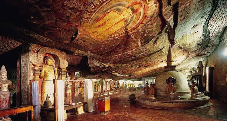 Rijk versierde binnenkant van Dambulla Cave Temple met Boeddhabeelden, muurschilderingen en een stupa onder een rotsdak.