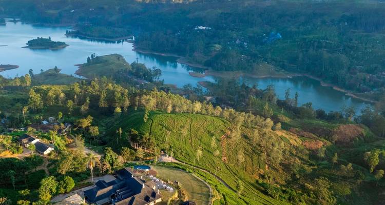Luchtfoto van rollende theeplantages, meren en verspreid liggende dorpjes in het bergland van Sri Lanka.