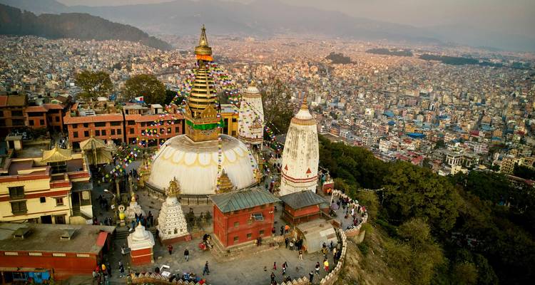 Vista aérea al atardecer de la estupa Swayambhunath que domina el amplio panorama de la ciudad de Katmandú y las colinas circundantes.