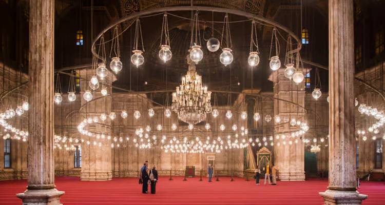 Gran salón de la Mezquita de Mohamed Ali con luces esféricas concéntricas colgando sobre una alfombra roja.