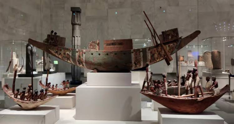 Antiguos botes funerarios de madera exhibidos en vitrinas dentro del Museo Egipcio.