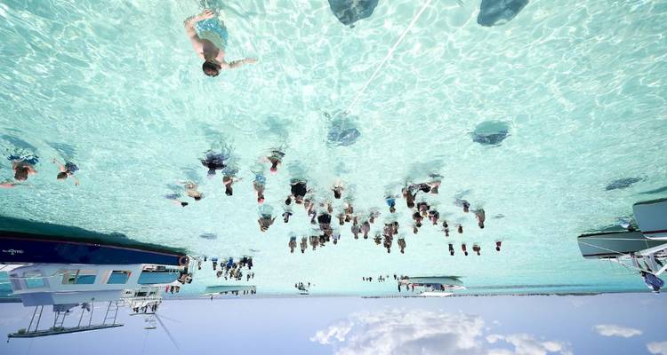 Vue aérienne de nombreux nageurs et bateaux dans une eau peu profonde des Caraïbes cristalline.