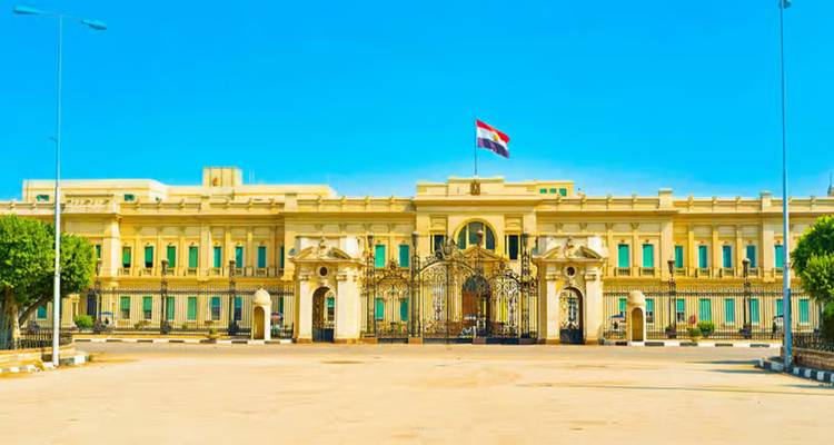 Palacio Abdeen neoclásico con la bandera egipcia ondeando bajo un cielo azul despejado.