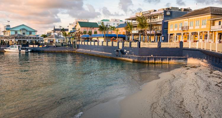 Les bâtiments colorés du front de mer et la petite jetée se reflétant dans les eaux calmes du soir à George Town.
