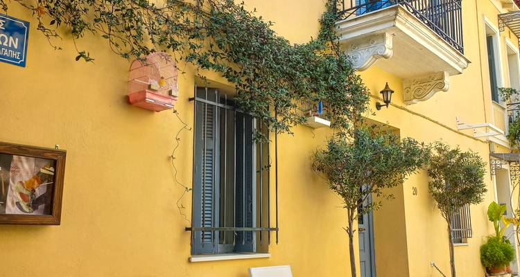 Charmante gele gevel van een Mediterraans huis met groen en balkondetails