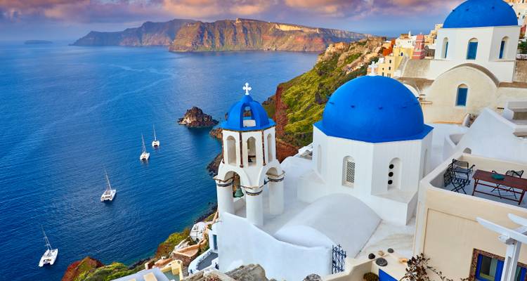 Klassiek prentbriefkaartje uitzicht van Santorini's blauwe koepelkerk, klokkentoren en jachten onder de steile kliffen