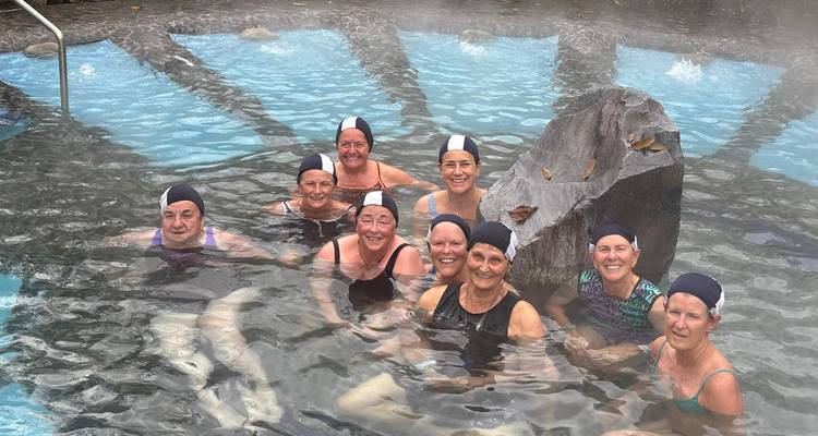 Des femmes souriantes portant des bonnets de bain profitent d'une piscine thermale extérieure fumante