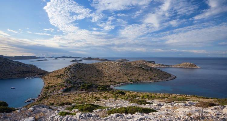 Felsige Inseln und türkisfarbene Buchten prägen die Adria unter einem wolkigen Himmel in Kornati