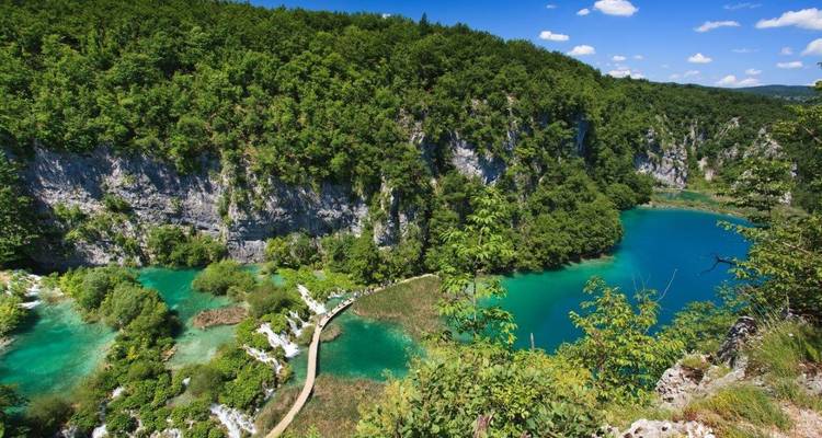 Smaragdgrüne Seen und bewaldete Klippen, verbunden durch hölzerne Stege im Nationalpark Plitvicer Seen
