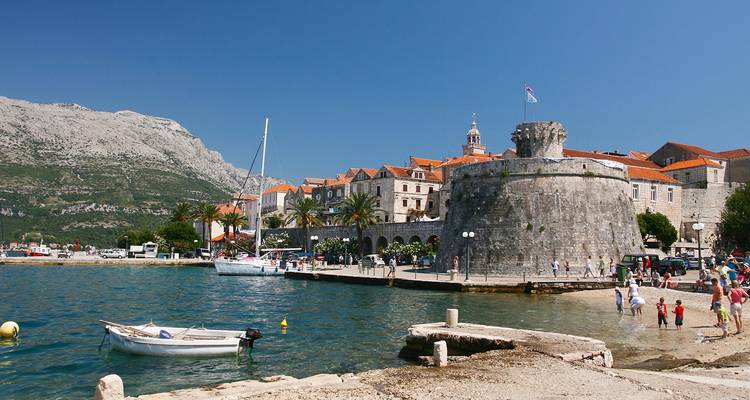 Stenen fortuin toren en waterfront van Korcula stad met bergen op de achtergrond