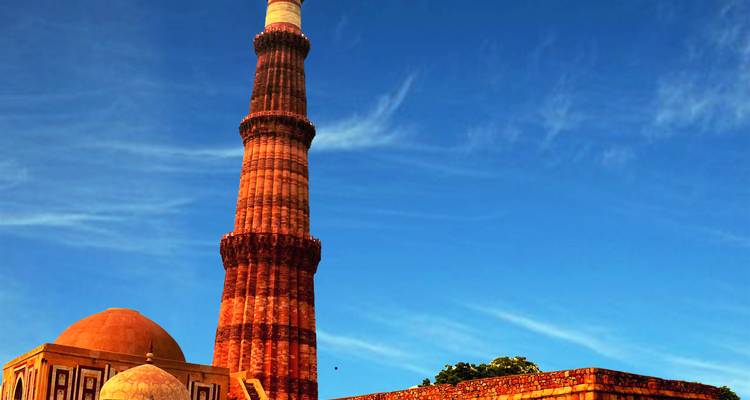 De imposante rode zandsteen Qutub Minar toren steekt af tegen de diepe blauwe Delhi lucht.
