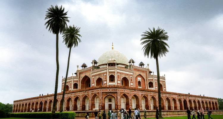Humayun's Tomb, een UNESCO-mausoleum van rode zandsteenlagen, staat te midden van zwaaiende palmbomen en bewolkte hemels.
