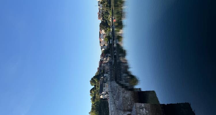 Ciel bleu clair au-dessus d'une ville portuaire tranquille parfaitement reflétée sur l'eau calme à l'aube.