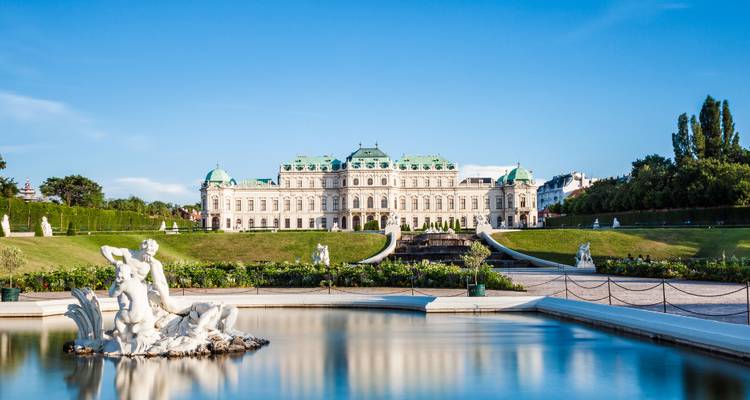 Le palais Belvédère élégant avec bassin réfléchissant et jardins entretenus sous un ciel bleu dégagé.