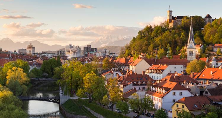 Panorama ensoleillée de la vieille ville de Ljubljana, de la rivière et du château, avec les Alpes enneigées en arrière-plan.