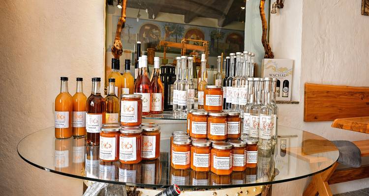 Exhibición de mermeladas locales, licores y bebidas espirituosas sobre una mesa de vidrio dentro de una tienda artesanal.