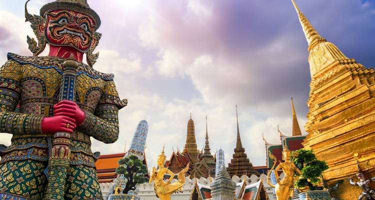 Complexe du Grand Palais avec une géante statue de gardien yaksha et un chedi doré sous un ciel dramatique.