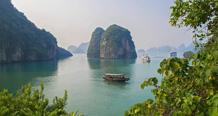 Les eaux émeraude sereines et les imposants pics calcaires parsemés de bateaux dans la baie d'Ha Long