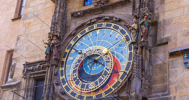 Gros plan de l'horloge astronomique ornée de Prague sur une ancienne façade en pierre avec des détails or, bleu et rouge éclatants.