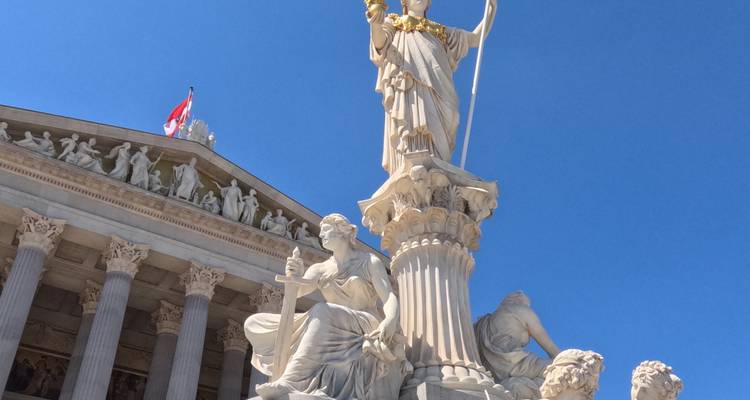 Statue d'Athéna devant le bâtiment du Parlement autrichien sous un ciel dégagé.