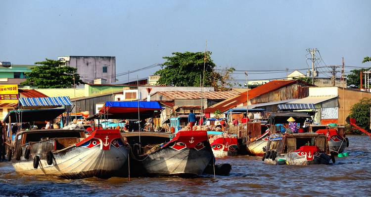 Marché flottant animé avec les étaves vivement peintes de bateaux en bois serrés les uns contre les autres sur une rivière boueuse.