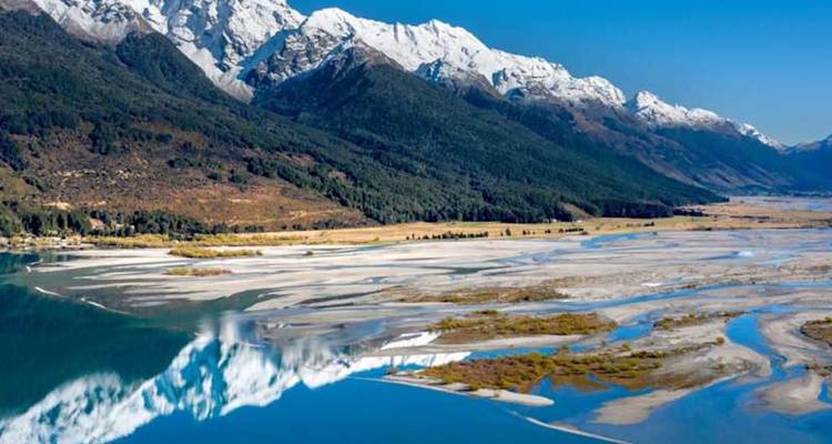 Les Alpes du Sud enneigées se reflétant dans un delta fluvial tressé et un lac turquoise