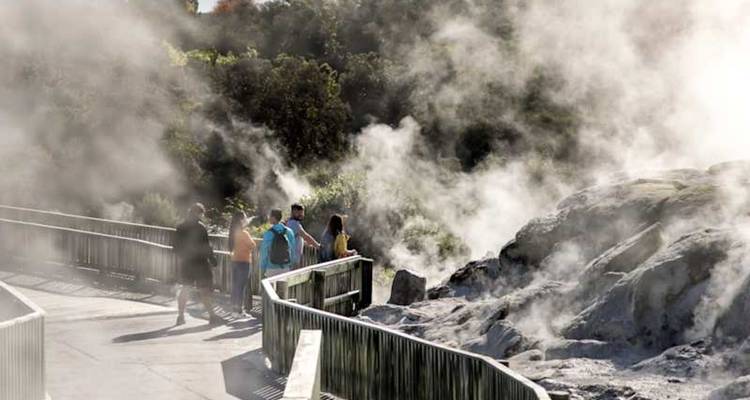 Les visiteurs se promènent sur une promenade au milieu d'une épaisse vapeur géothermale s'échappant des évents et des bassins rocheux.