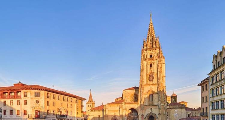 Catedral gótica iluminada por el sol que domina la plaza de Oviedo bajo un cielo azul despejado