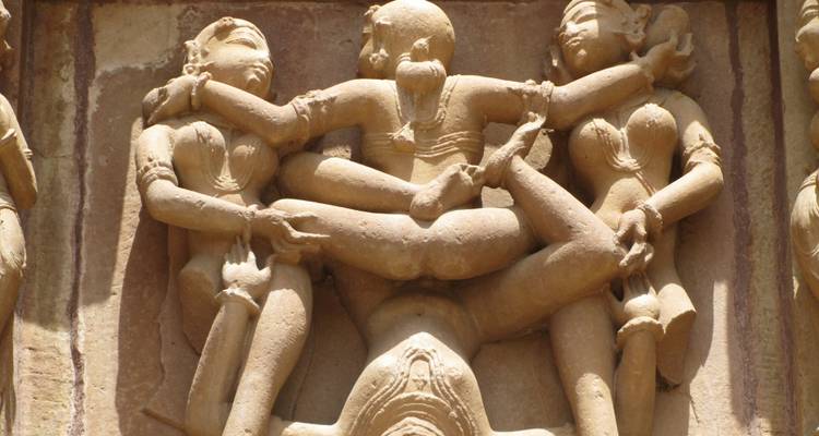 Nahaufnahme einer erotischen Sandsteinskulptur, die verschlungene Figuren an einem antiken Tempel darstellt.