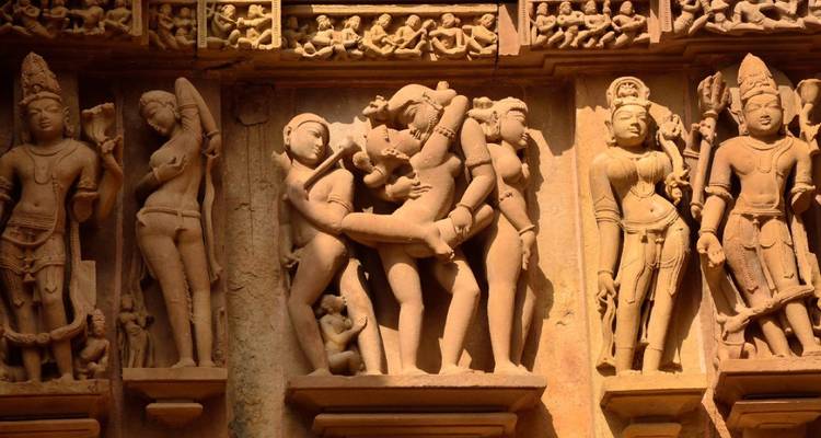 Tafel mit kunstvollen und sinnlichen Steinmetzarbeiten an der Fassade eines Khajuraho-Tempels.