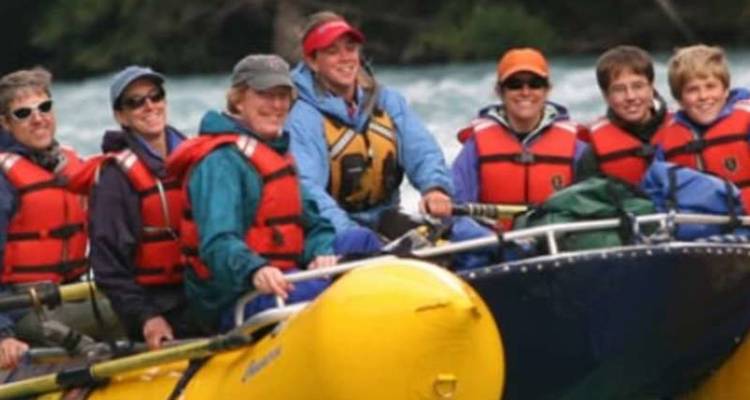 Un groupe portant des gilets de sauvetage rouges navigue sur un radeau jaune à travers des rapides calmes.