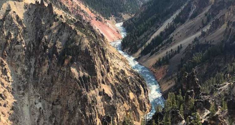Des parois de canyon multicolores et abruptes encadrent une rivière bleue sinueuse bien en dessous sous un ciel dégagé