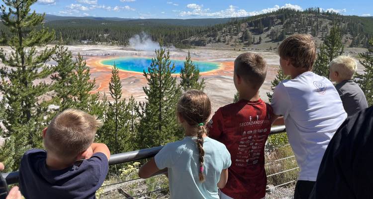 Les enfants s'appuient contre une rambarde surplombant les couleurs vibrantes de la source Grand Prismatic.