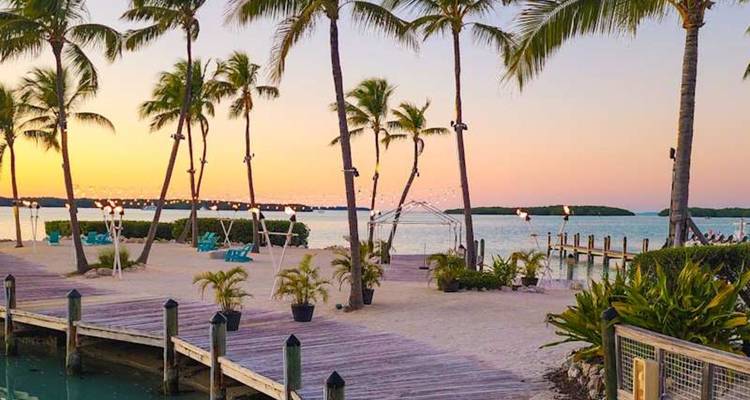 Palmbeplante zandige boulevard met uitzicht op kalm turquoise water bij zonsondergang in de Keys