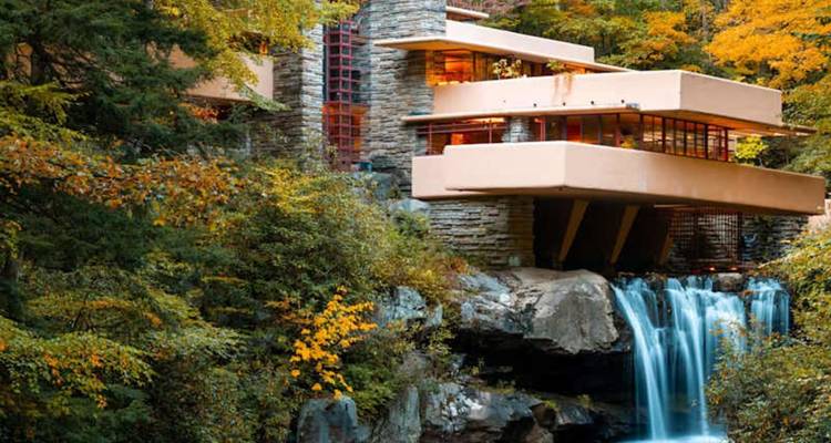 Het iconische Fallingwater-huis van Frank Lloyd Wright hangt boven een cascade watervallen temidden van weelderig herfstgebladerte.