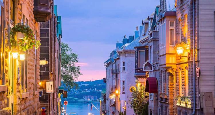 Charmante rue pavée dans le Vieux-Québec bordée de bâtiments historiques illuminés par des lampadaires du soir
