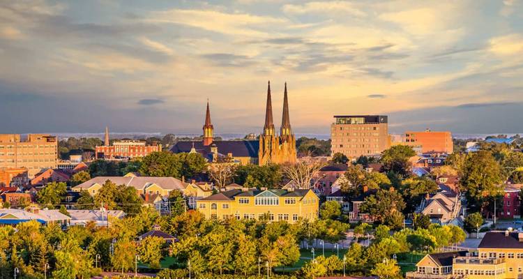 Horizon urbain de Charlottetown avec des flèches de cathédrale s'élevant au-dessus des rues bordées d'arbres à la lumière du coucher de soleil.