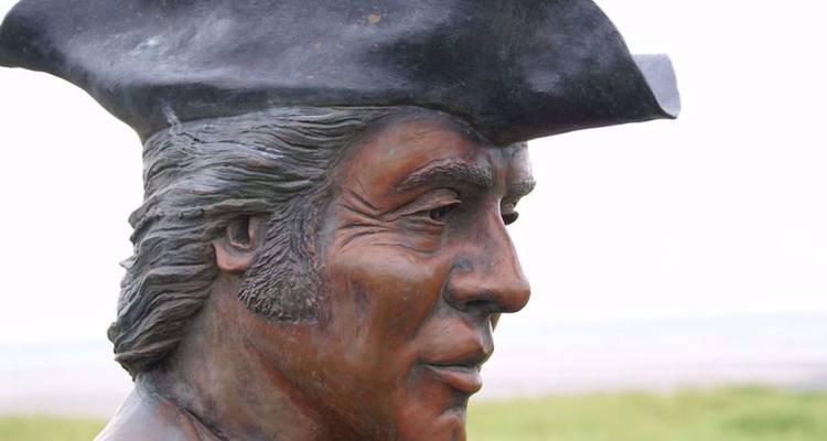 Bronzen buste van een verkenner met een driehoekige hoed tegen een lichte lucht
