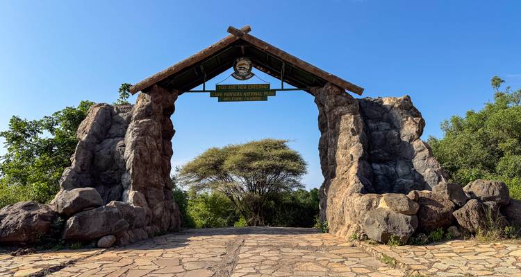 Arco de piedra marcando la entrada al Parque Nacional del Lago Manyara en un día soleado.