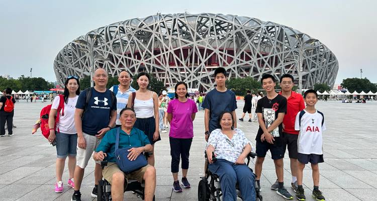 Un grupo familiar grande posando en una plaza abierta frente al Estadio Nacional Nido de Pájaro de Beijing.