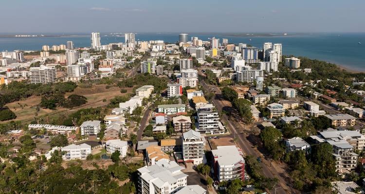 Panorama aérien d'une ville côtière avec des immeubles de grande hauteur, des espaces verts et la mer bleue s'étendant jusqu'à l'horizon