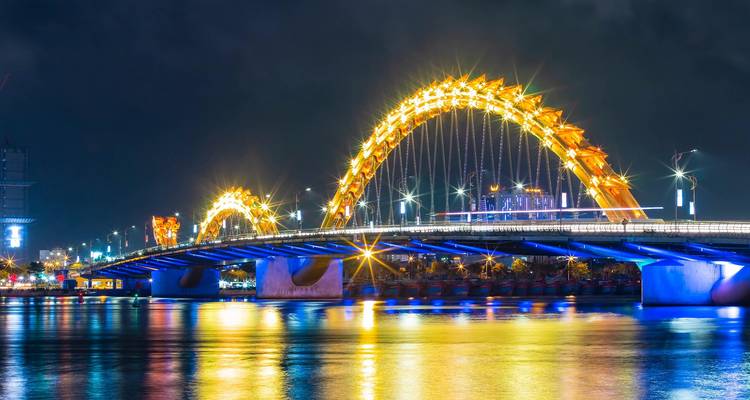 Vue nocturne du Pont du Dragon de Da Nang, magnifiquement illuminé, qui enjambe la rivière Han avec ses reflets scintillants.