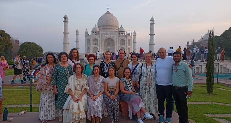 Große Reisegruppe, die sich bei Dämmerungslicht vor dem Taj Mahal zusammen fotografieren lässt.