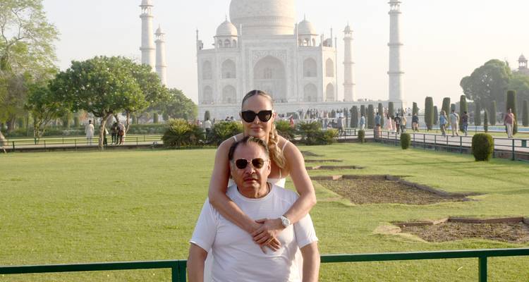 Paar in Umarmung mit dem Taj Mahal und gepflegten Rasenflächen im Hintergrund.