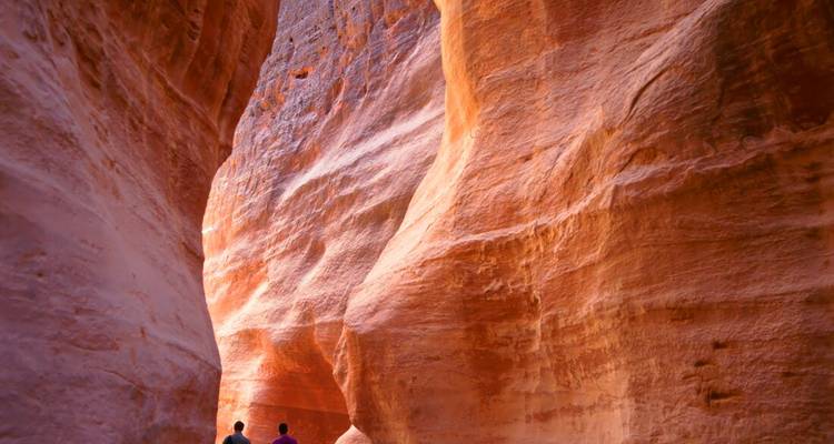Les visiteurs qui marchent à travers les hauts murs de grès rose-rouge du canyon du Siq